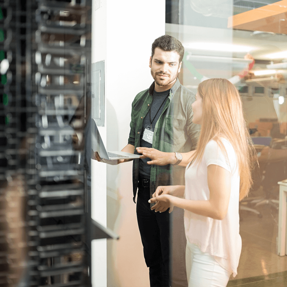 Zwei Kollegen unterhalten sich vor dem Serverschrank über revisionssichere Archivierung