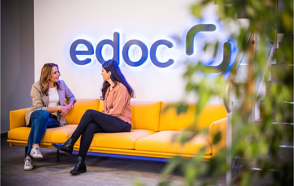 Zwei ECM-Spezialistinnen von edoc sitzen auf einem gelben Sofa und unterhalten sich