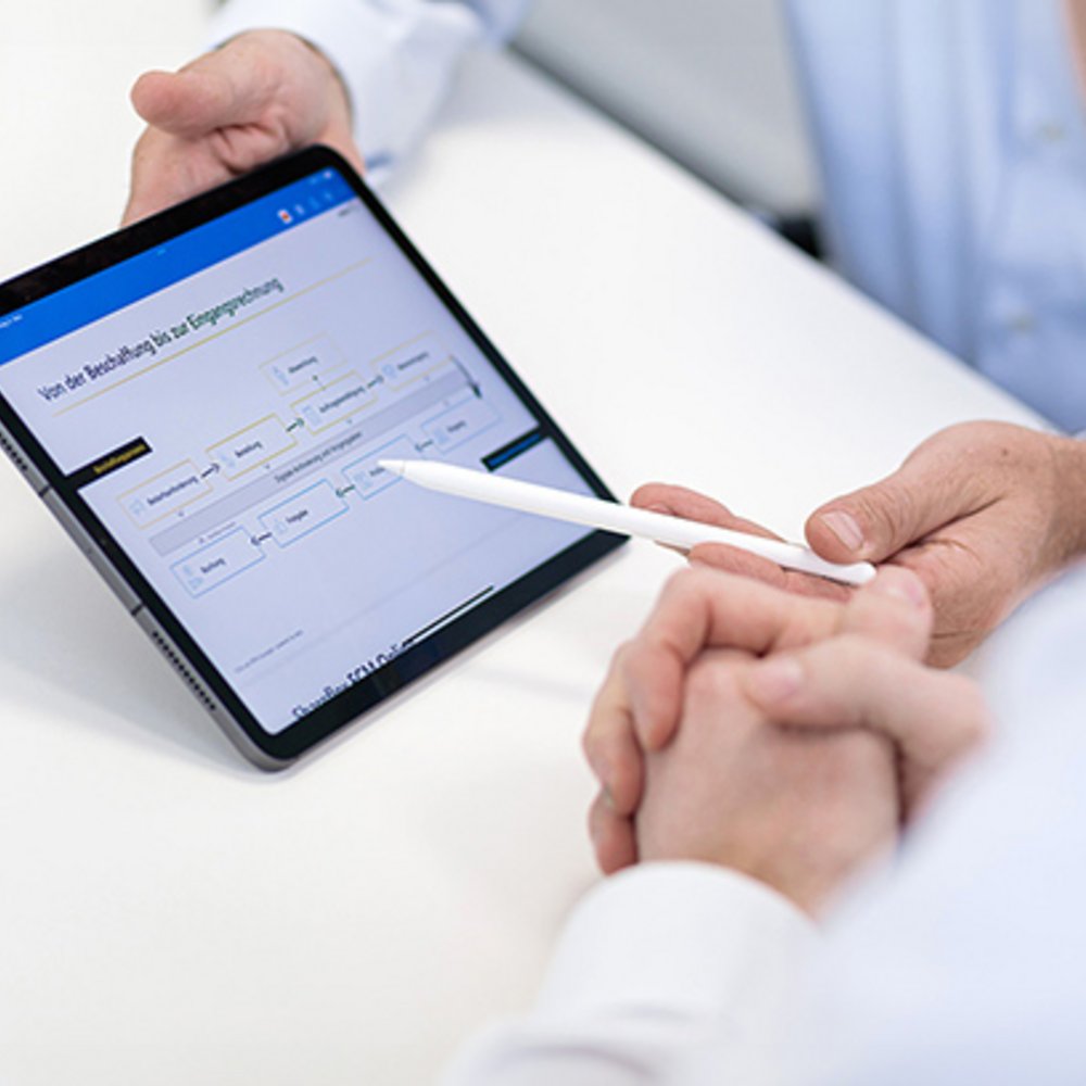 Zwei Mitarbeiter von edoc schauen auf ein Ipad mit geöffneter App.