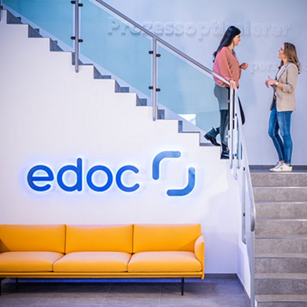 Zwei Mitarbeiterinnen der edoc solutions ag stehen auf einer Treppe und unterhalten sich.