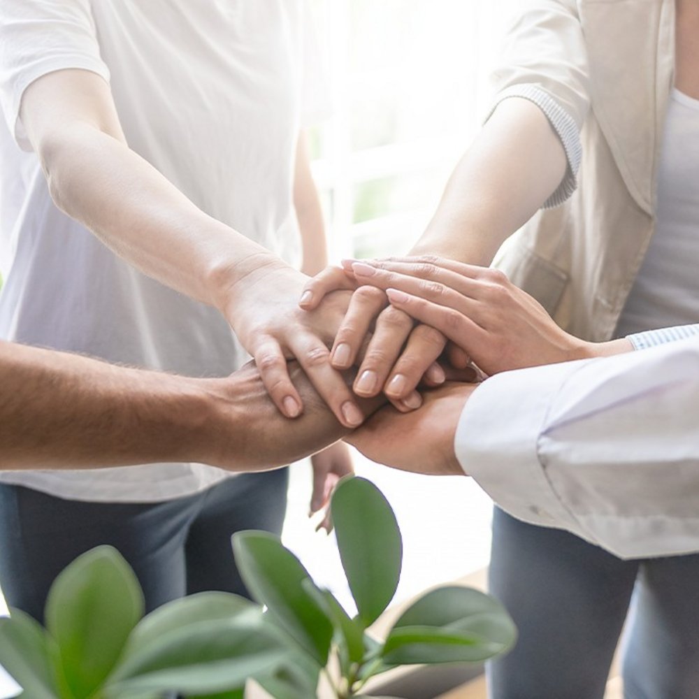 edoc blog vier Mitarbeitende legen die Hände zusammen für Teamwork, Zusammenhalt und optimale Zusammenarbeit