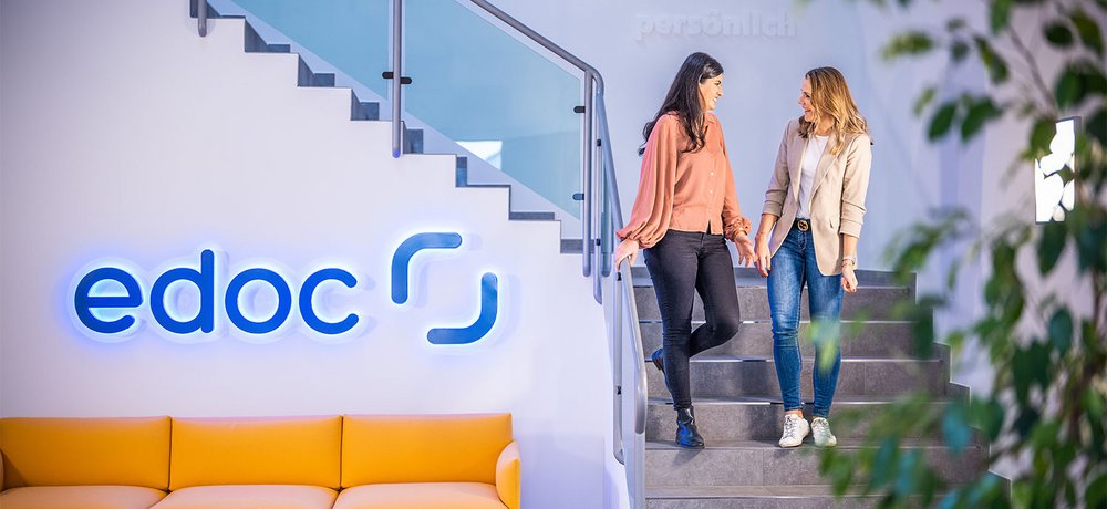 Zwei Mitarbeiterinnen der edoc Solutions AG stehen auf einer Treppe und unterhalten sich