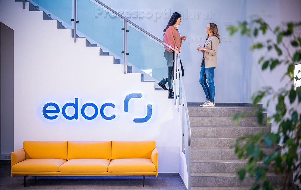 Zwei Mitarbeiterinnen der edoc Solutions AG stehen auf einer Treppe und unterhalten sich