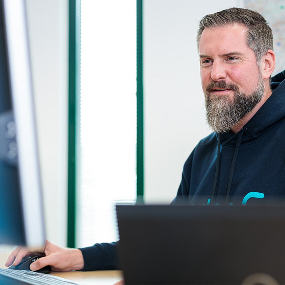 edoc Mitarbeiter sitzt am PC und arbeitet. 