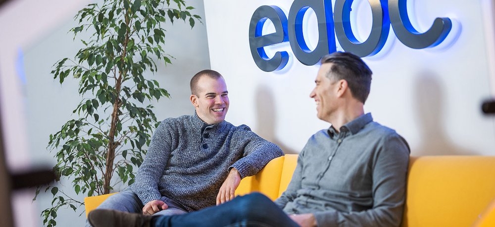 Zwei edoc Mitarbeiter sitzen auf einem gelben Sofa und unterhalten sich über digitale ECM-Lösungen für ERP-Systeme