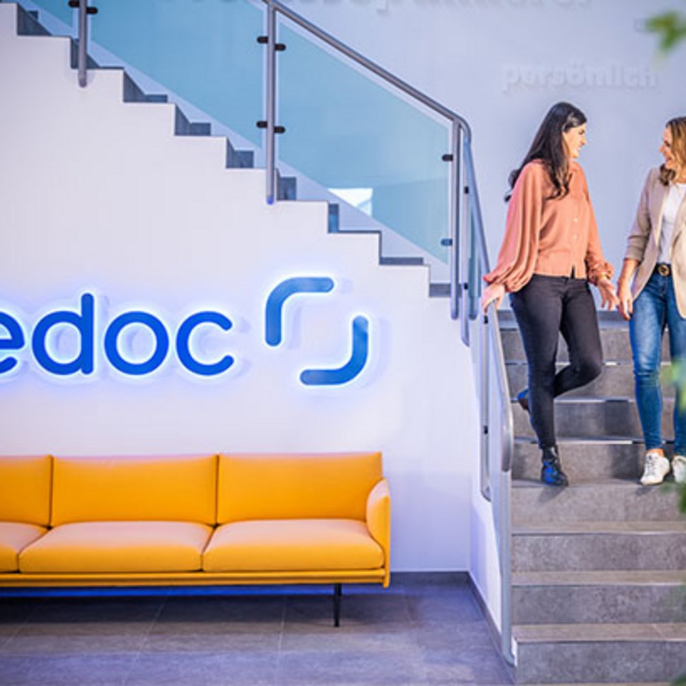 Zwei Mitarbeiterinnen der edoc solutions ag stehen auf einer Treppe und unterhalten sich.